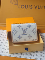 Light blue mini wallet with blue patterned exterior and foldover front in a box