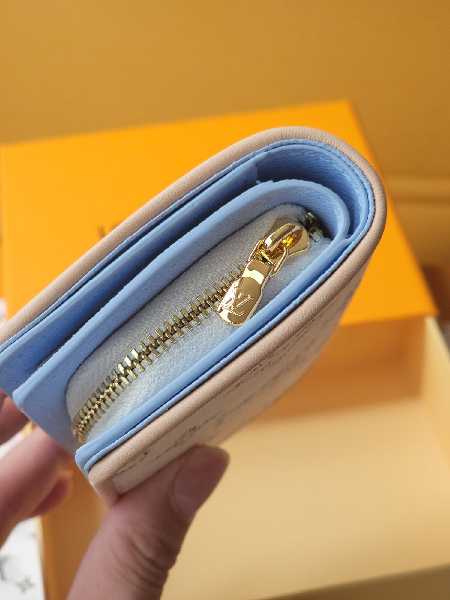 Light blue mini wallet close-up showing gold zipper and soft fabric interior