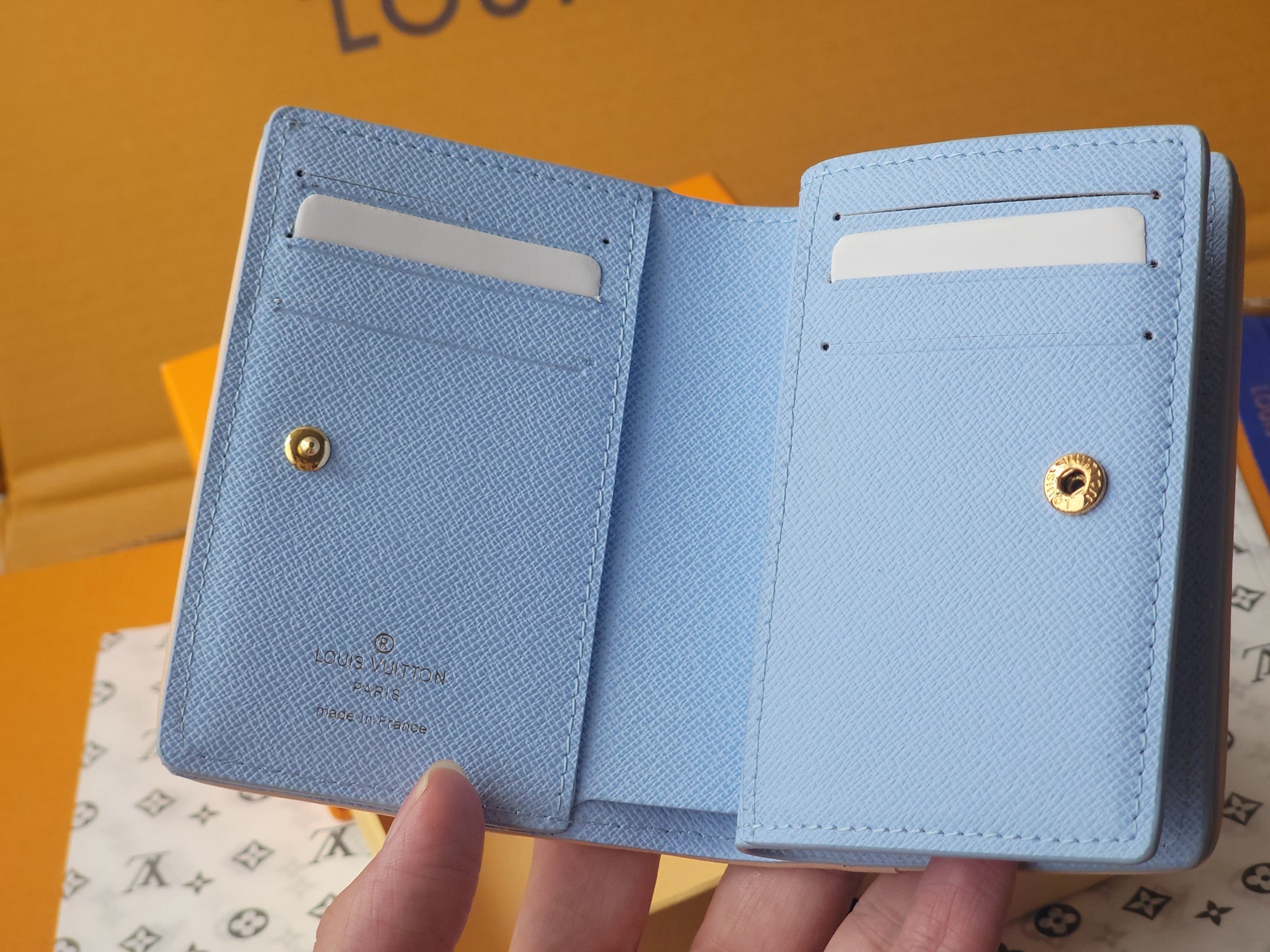 Light blue bifold mini wallet with two card slots and gold snap closure