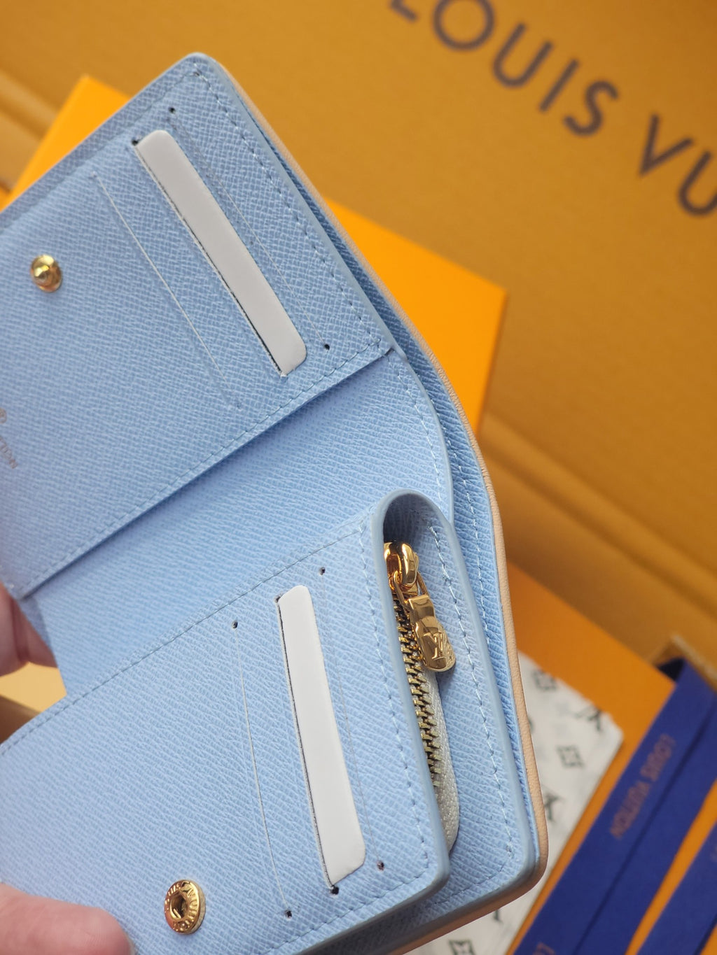 Light blue mini wallet close-up of front corner with gold hardware and snap
