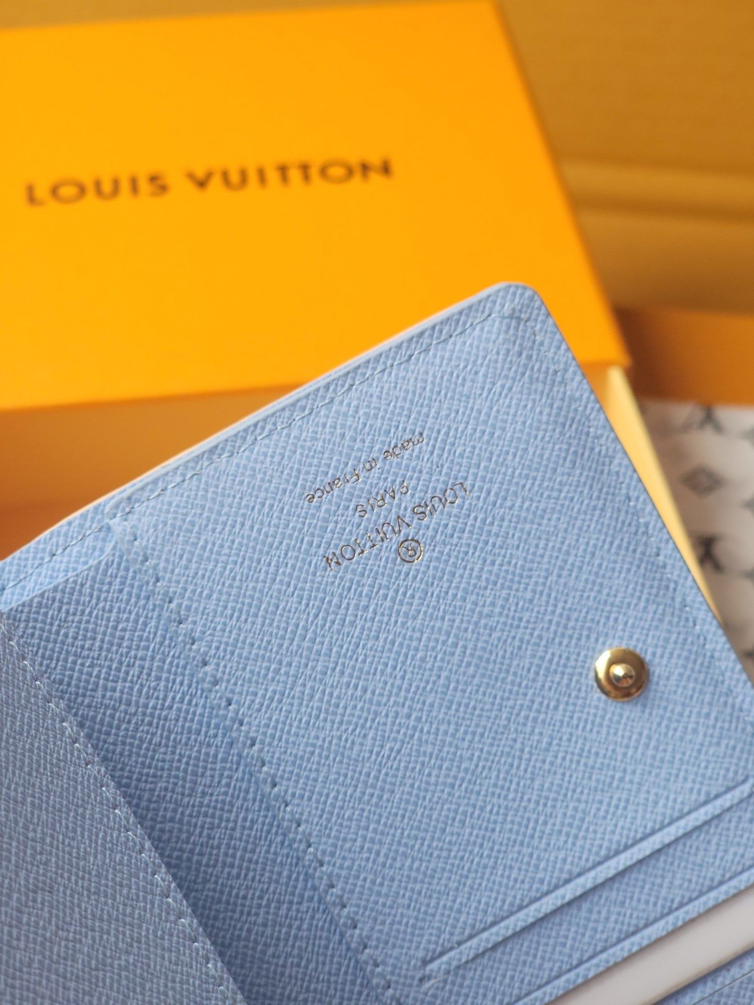 Light blue mini wallet close-up of textured fabric and gold snap button