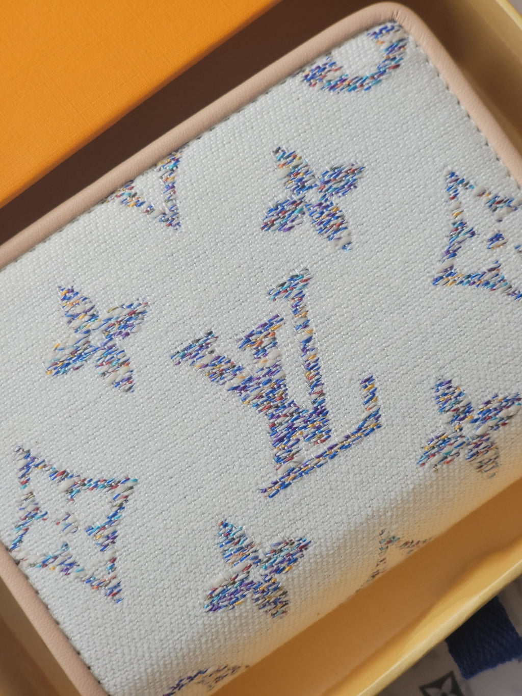 Light blue mini wallet with allover blue monogram-style pattern on textured fabric