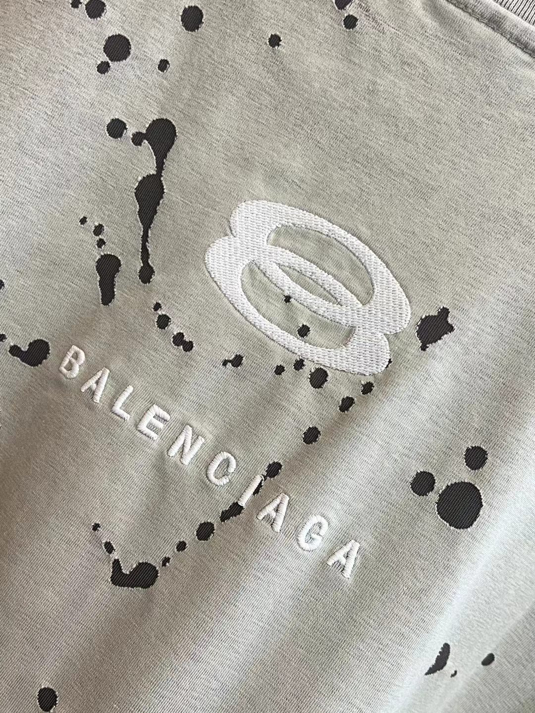 Light heather gray T-shirt with oval logo, black splatter dots, and BALENCIAGA lettering
