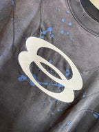 Balenciaga T-shirt chest close-up with white oval logo and blue paint-splatter marks