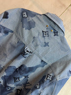 Long-sleeve shirt front close-up in light blue stripes with dark blue motif print and buttons