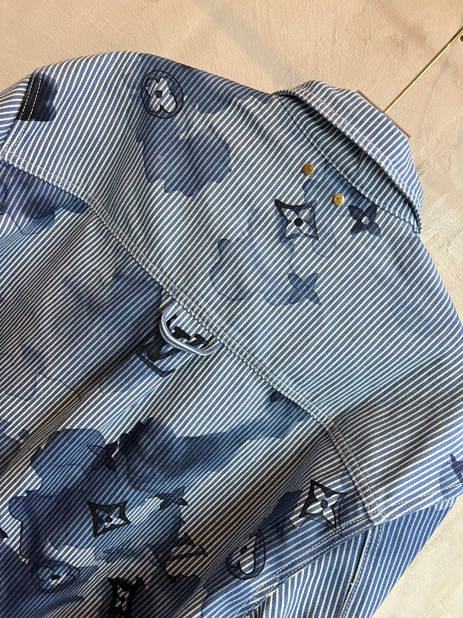 Long-sleeve shirt front close-up in light blue stripes with dark blue motif print and buttons