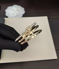 Gold-tone stacked bangles with crystal trim, shown in a black-gloved hand