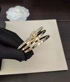 Gold-tone stacked bangles with crystal trim, shown in a black-gloved hand