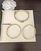 Three gold-tone bangles arranged on a box, with crystal details at clasp