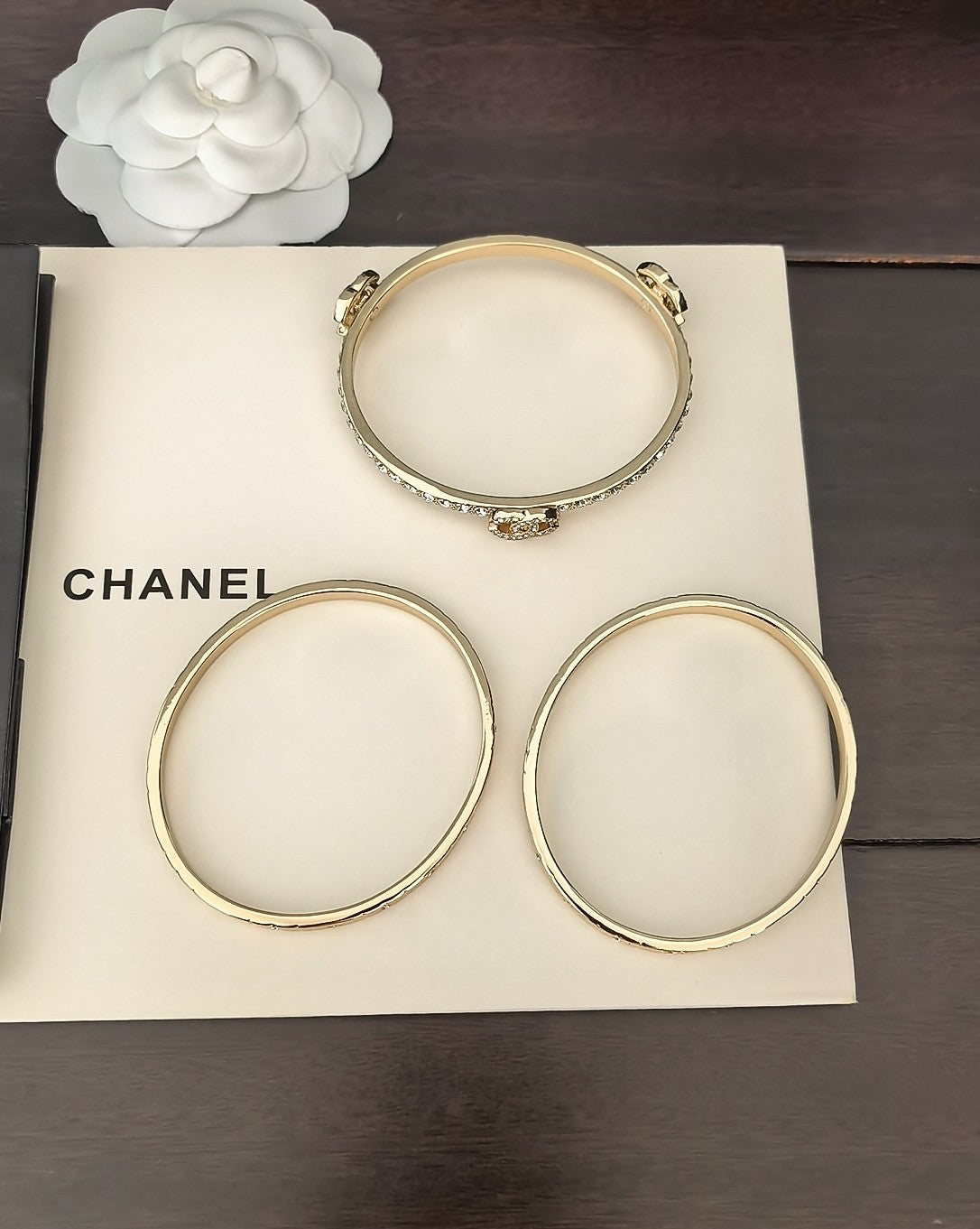 Three gold-tone bangles arranged on a box, with crystal details at clasp