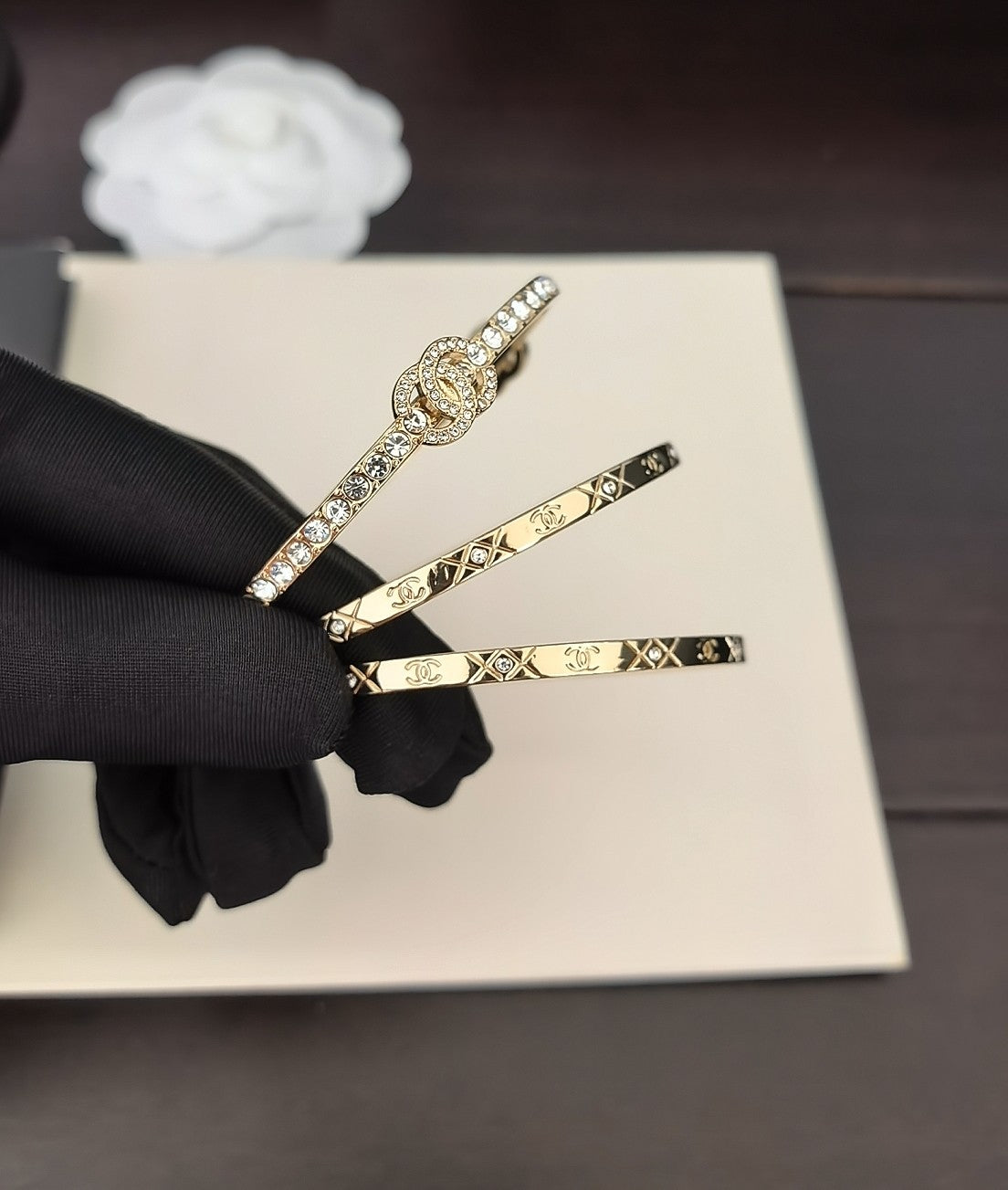 Gold-tone bangles with crystal accents on a black-gloved hand