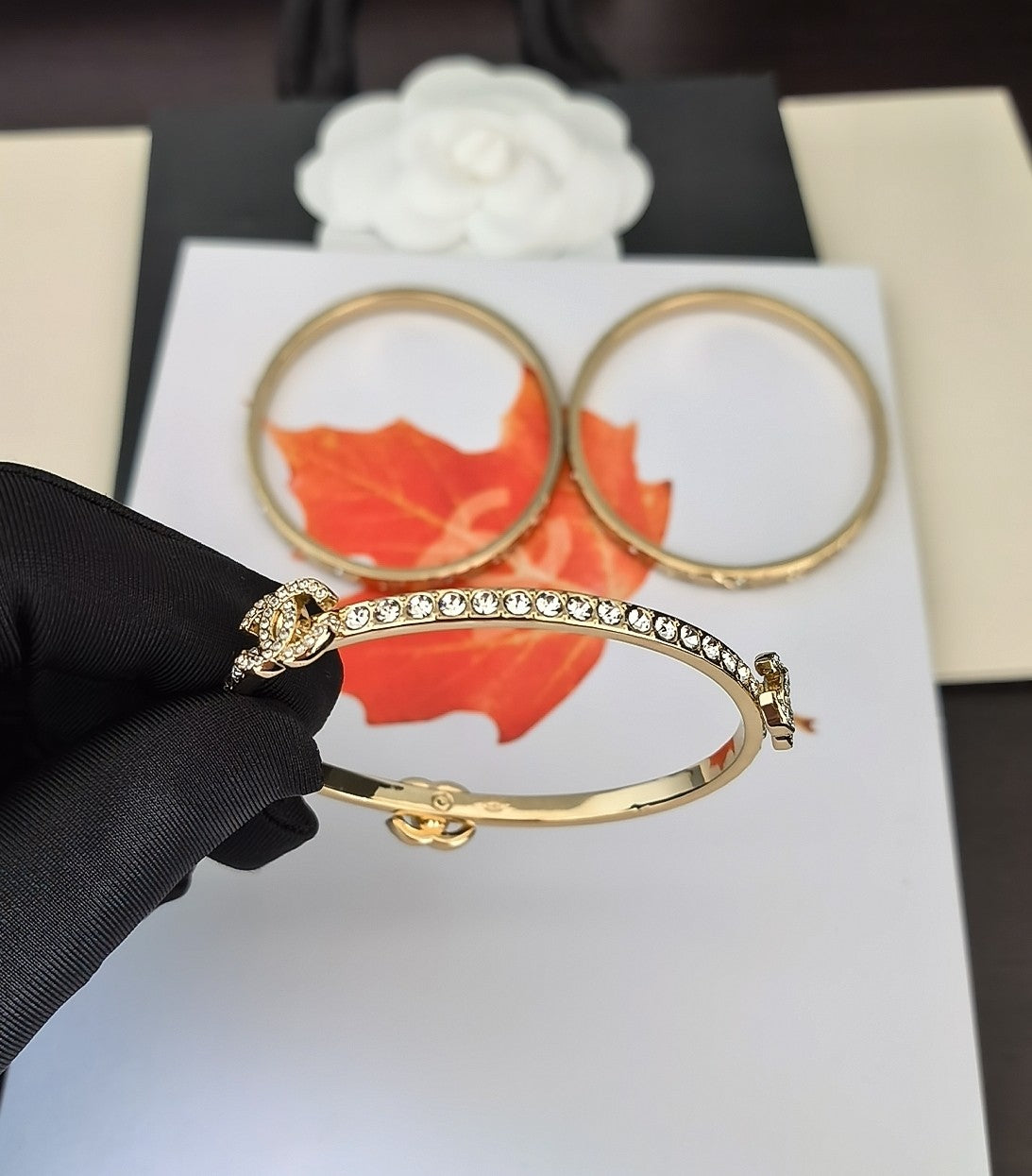 Gold-tone crystal bracelet with red enamel section, plus two gold bangles behind