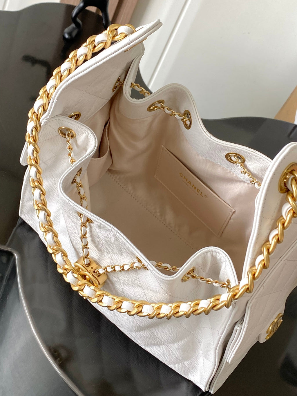 Open white Chanel shoulder bag with gold chain strap and quilted interior