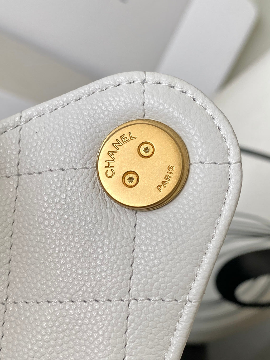 Round gold-tone Chanel logo medallion on white quilted leather bag