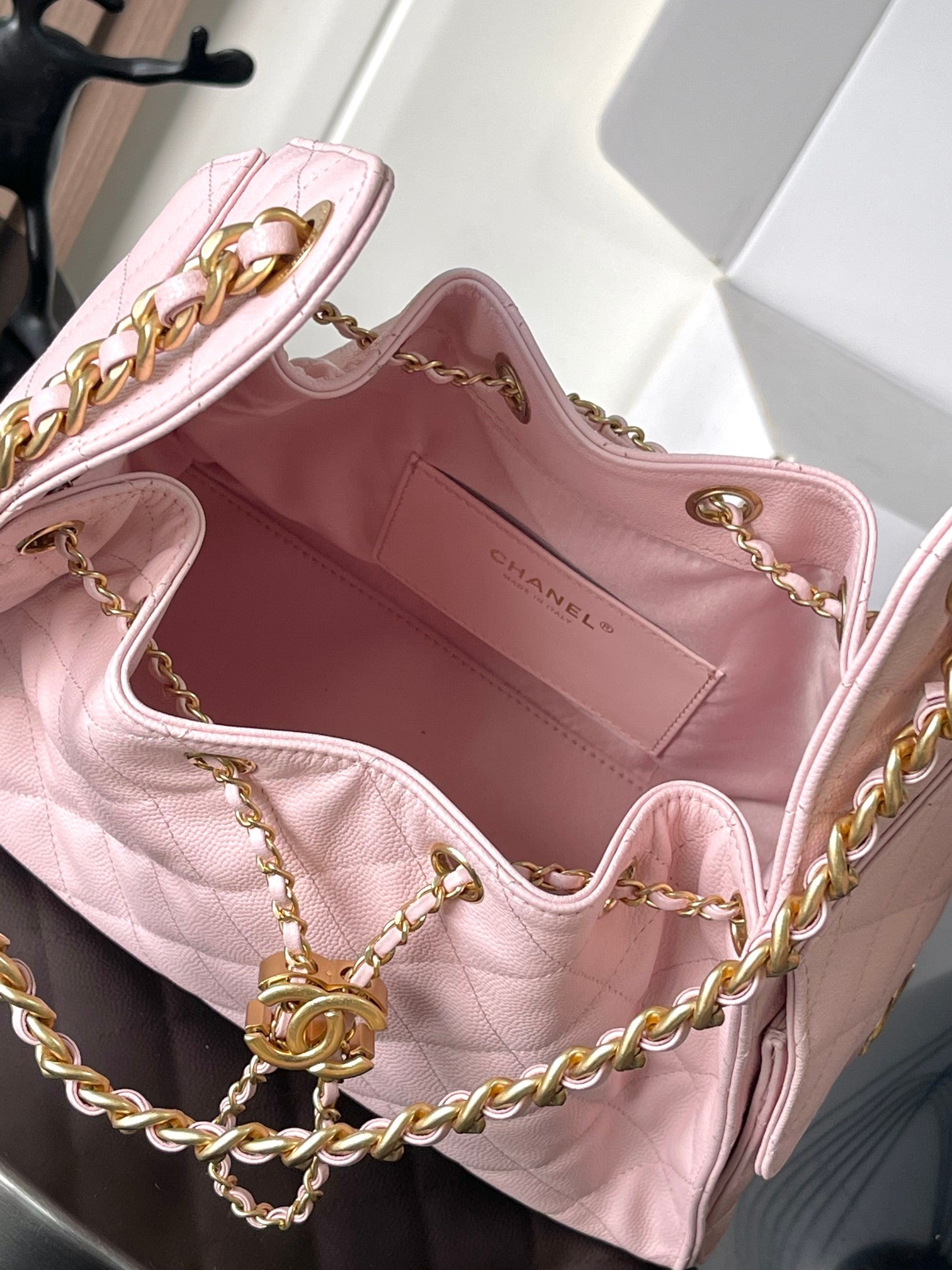 Open pink quilted Chanel bag interior with gold chain and clasp hardware