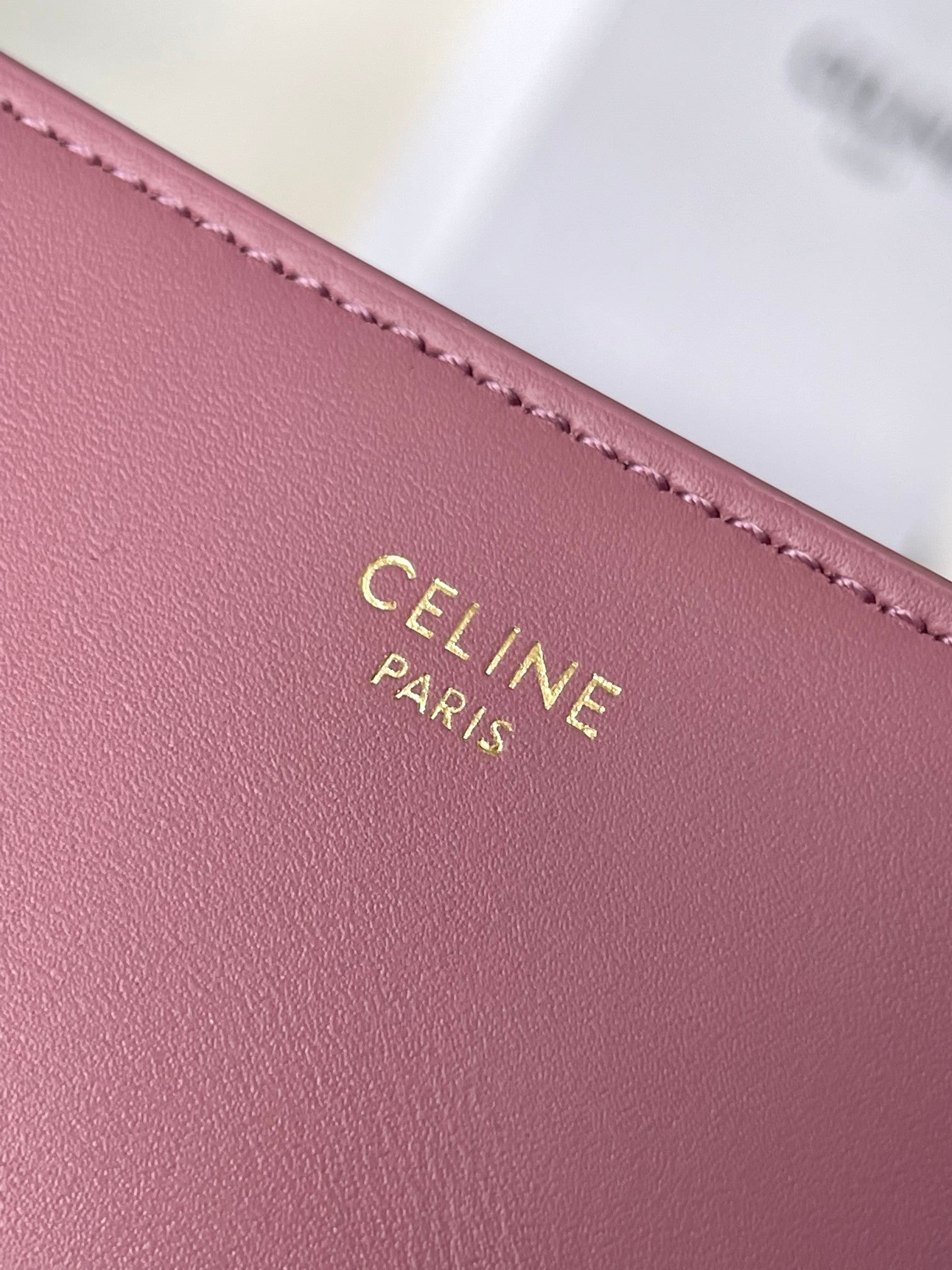 Pink leather Celine bag close-up of gold stamped CELINE PARIS text