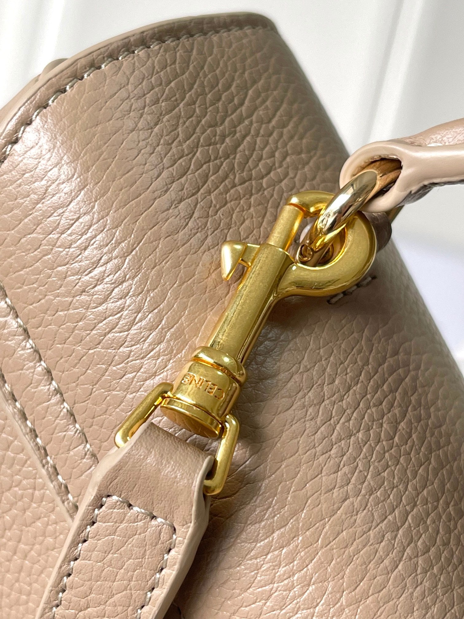 Celine gold-tone clasp and chain hardware on beige leather bag side