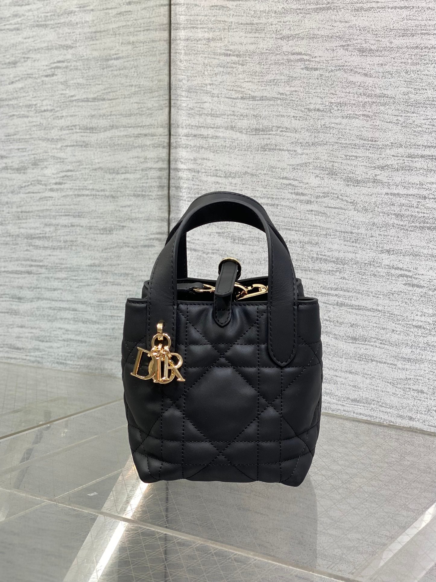 Black quilted Dior mini tote with small top handle, shoulder strap, and gold hardware