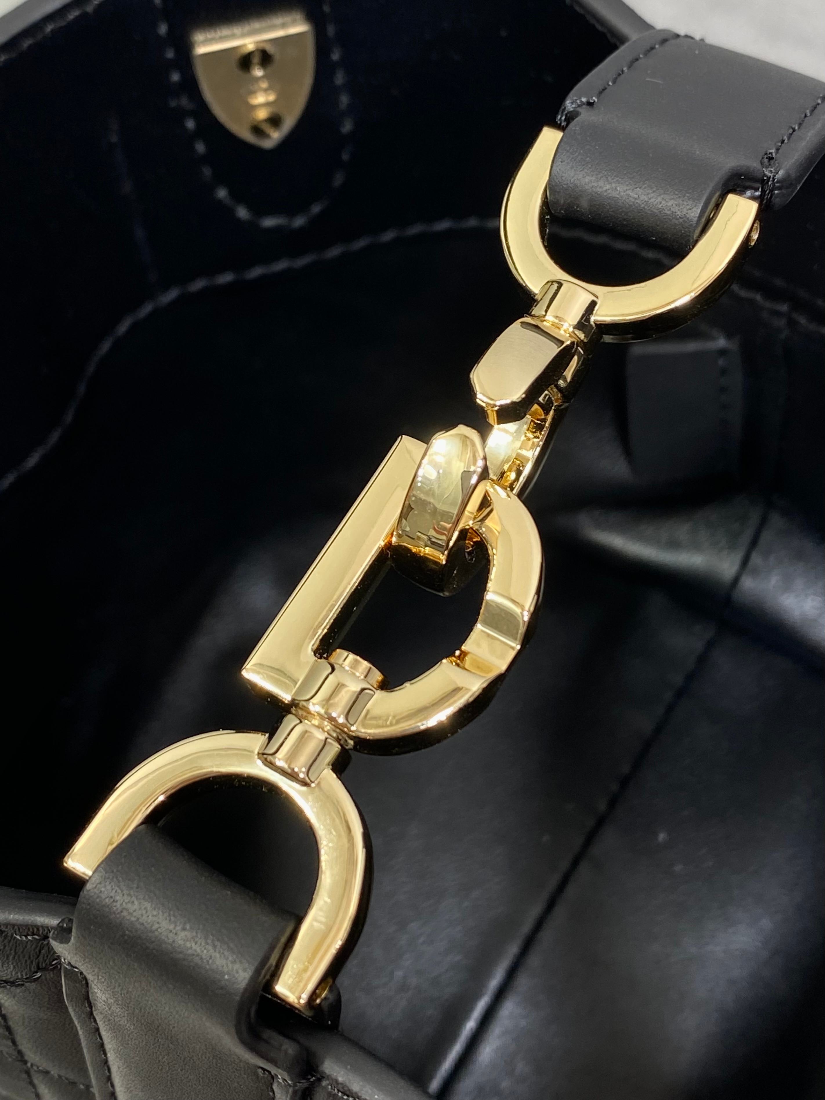 Gold-tone tote hardware with ring clasp on black quilted leather bag