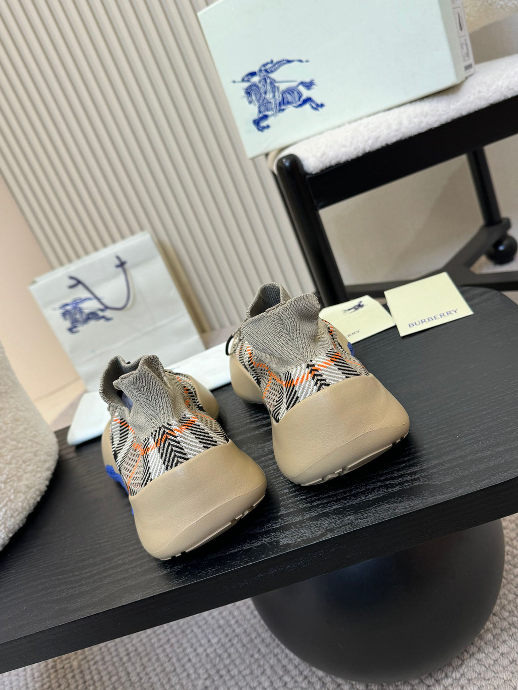 Back view of beige knit sneakers with black check pattern and blue outsole accents.