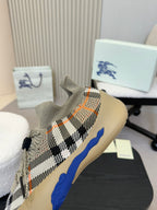 Front 3/4 view of beige knit sneaker with black check pattern and blue side stripe.
