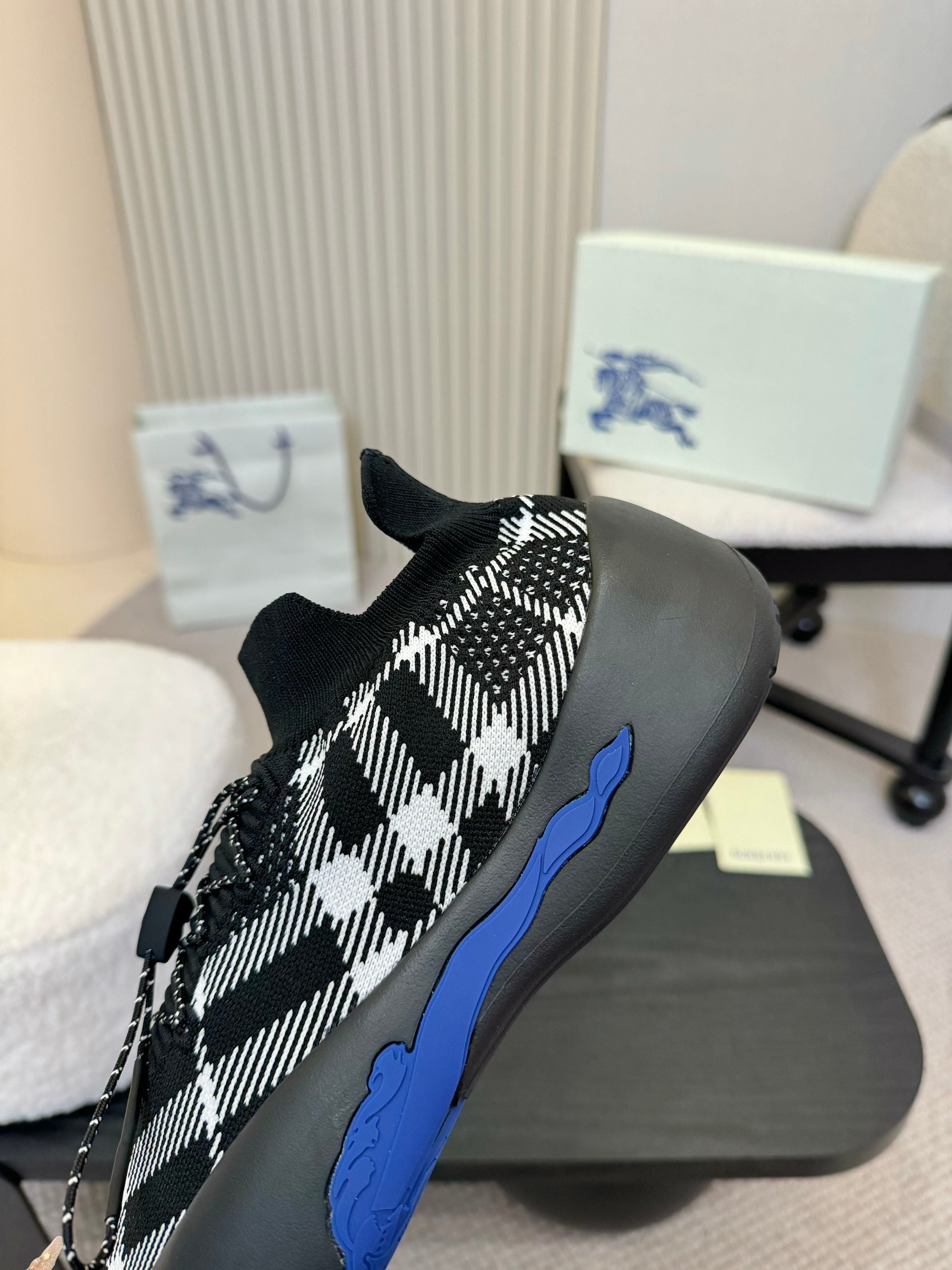 Side view of black slip-on sneaker with white check pattern and blue sole trim