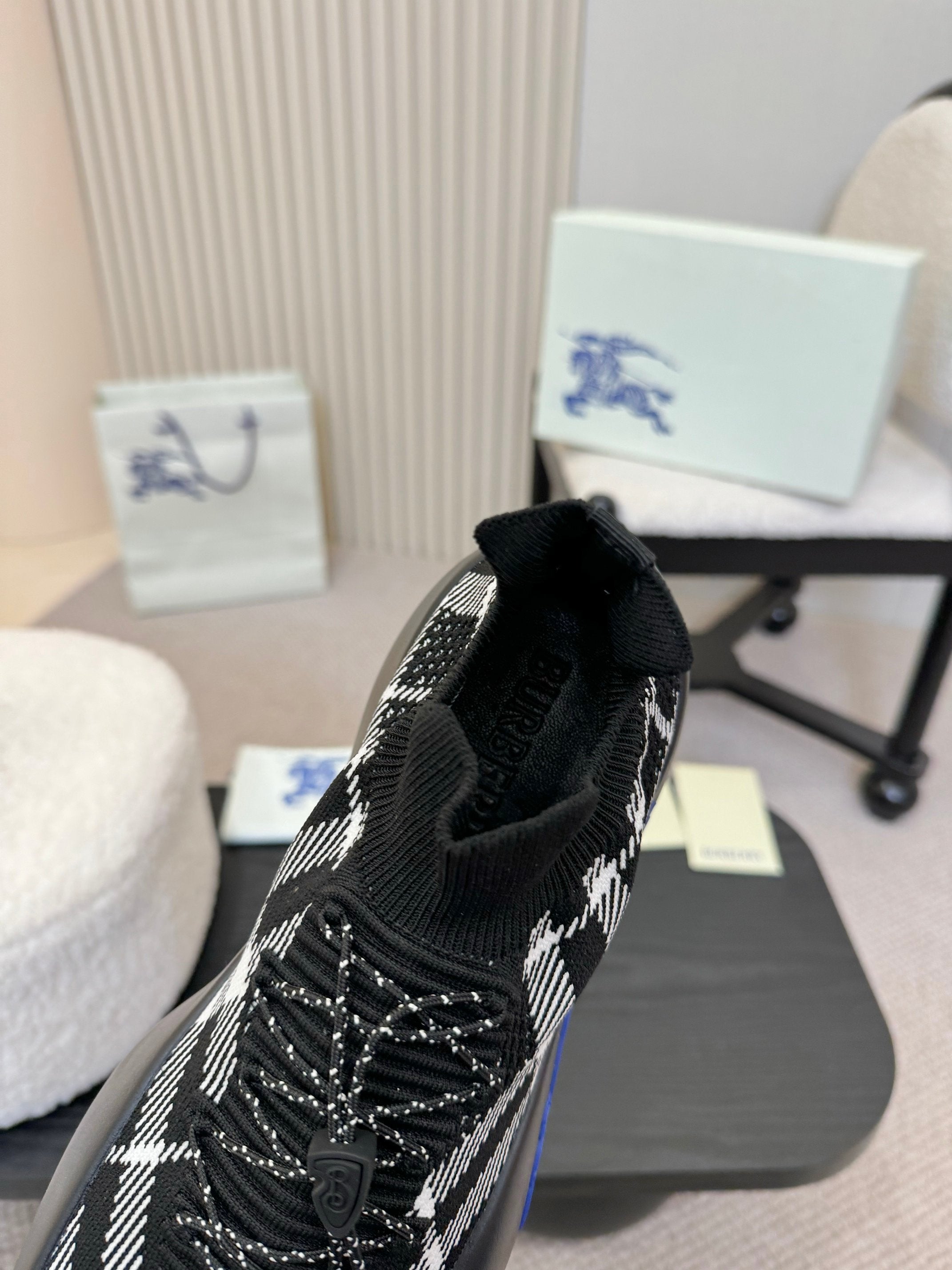 Black slip-on sneaker with white check knit panels and blue outsole accents