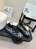 Pair of black slip-on sneakers with white check knit pattern and blue soles