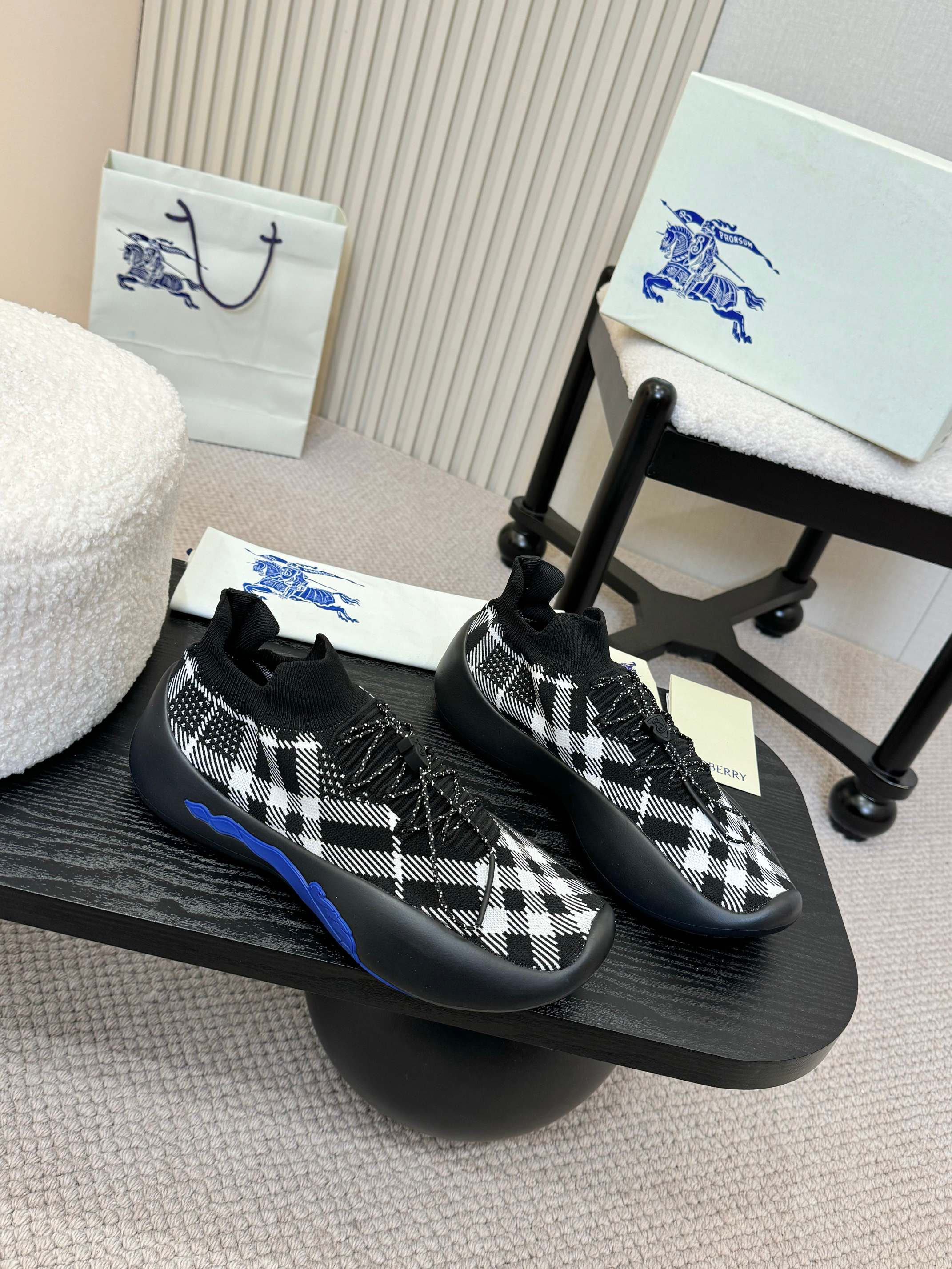 Pair of black slip-on sneakers with white check knit pattern and blue soles