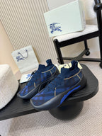 Burberry blue knit slip-on sneakers on black stand, plaid pattern, yellow stitching