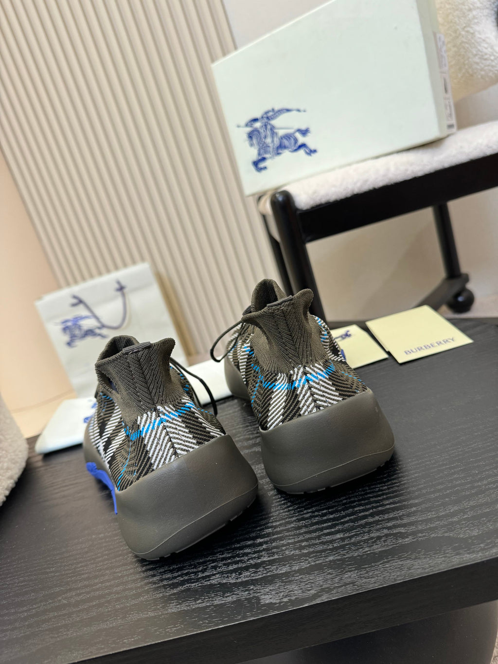 Back view of black and white checkered knit sneakers with blue heel detailing
