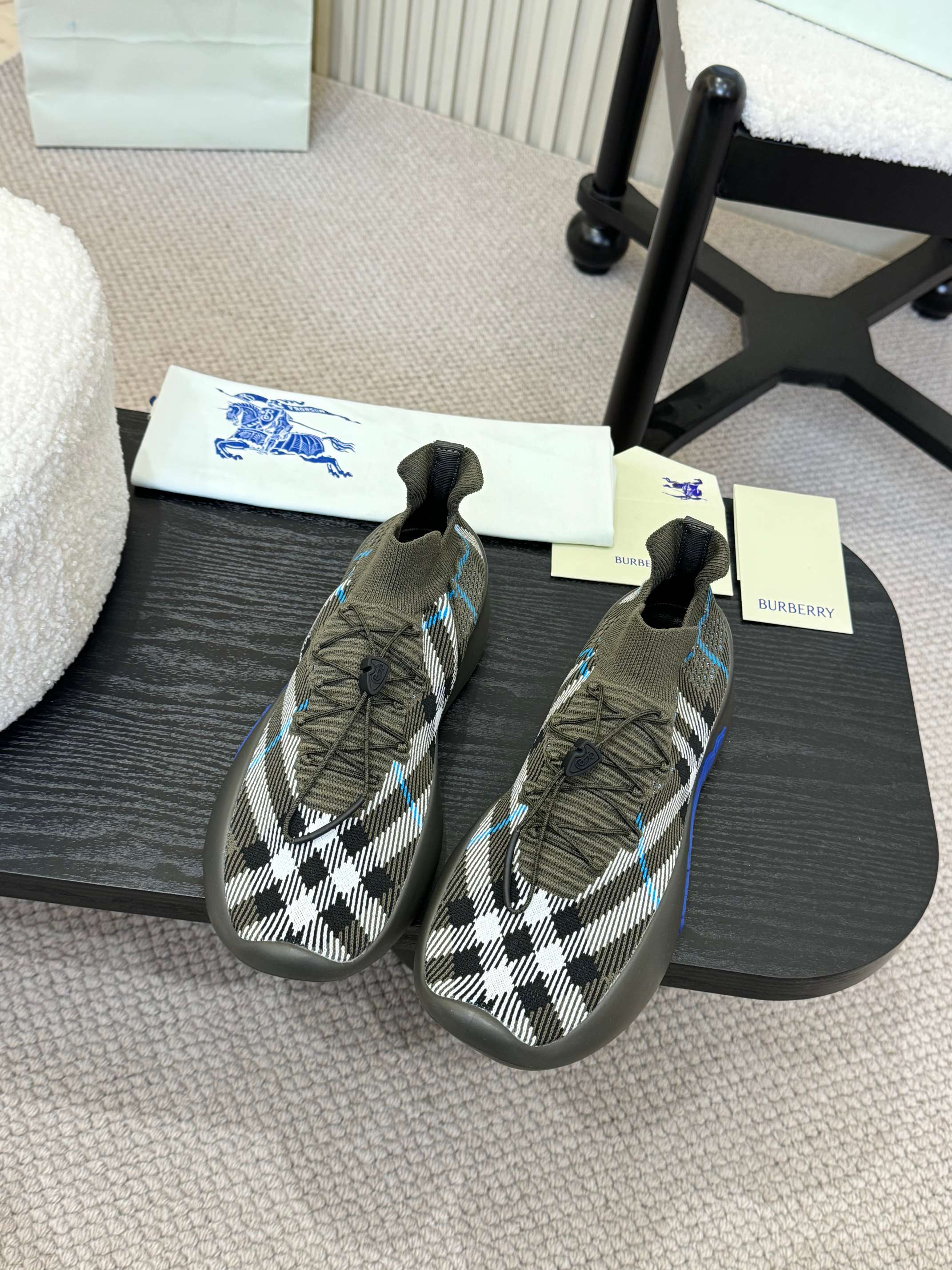 Pair of black and white checkered knit sneakers with blue trim and elastic collar