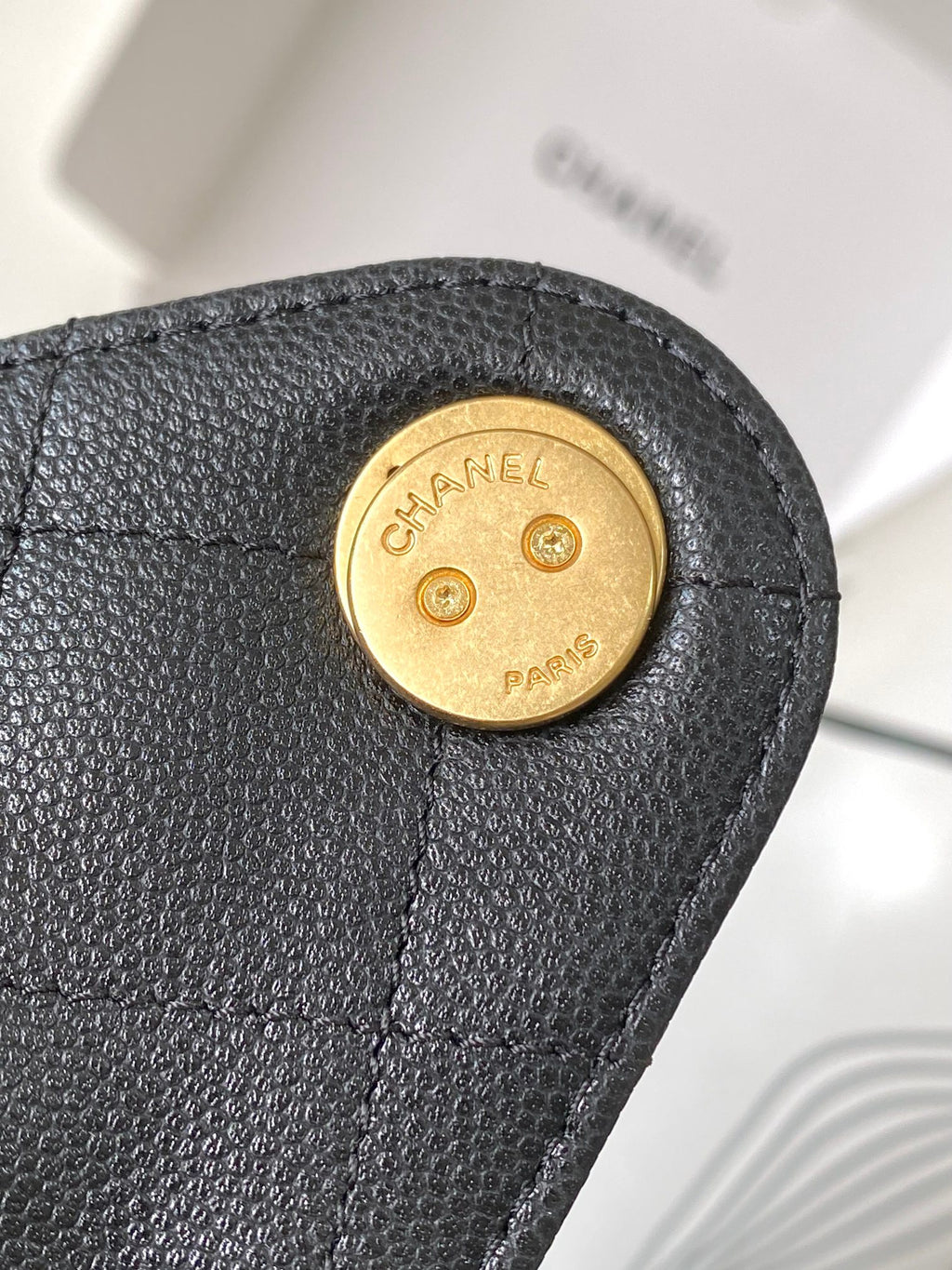 Chanel logo button hardware on dark gray textured leather flap