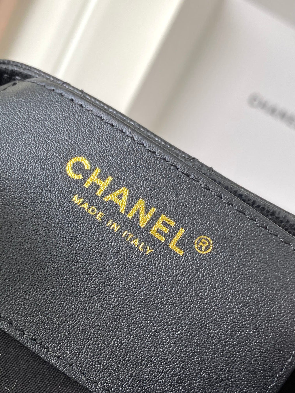 Chanel bag interior branding label in gold on dark gray leather