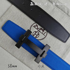 Blue Hermes belt with black buckle over; black belt lies behind.