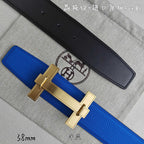 Blue Hermes belt with gold buckle over; black belt lies behind.