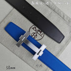 Blue Hermes belt with silver buckle over; black belt lies behind.