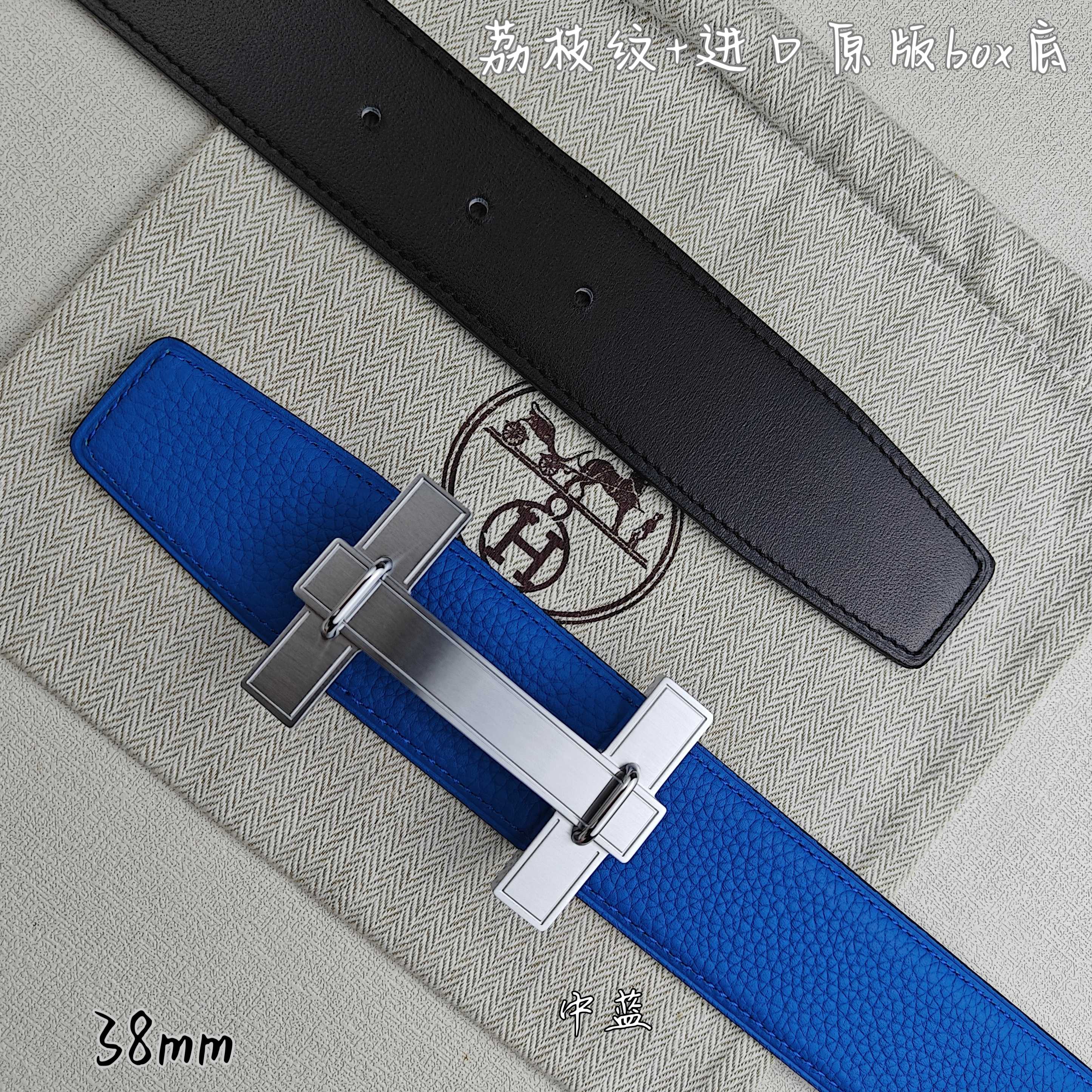 Blue Hermes belt with silver buckle over; black belt lies behind.