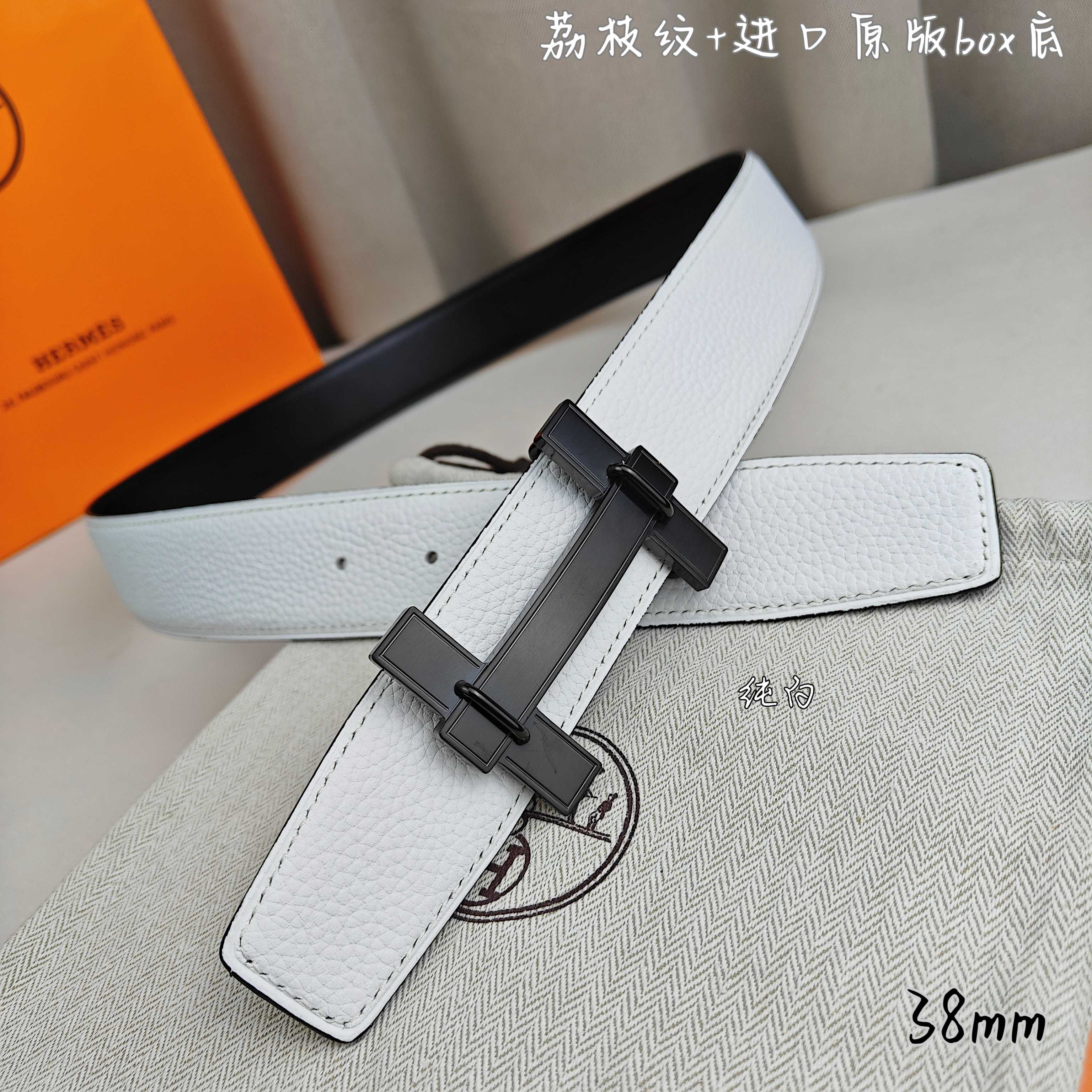 White leather belt with dark charcoal buckle and long strap keeper.