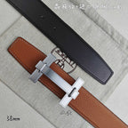 Hermes belt with tan leather and black underside, silver-tone buckle detail.