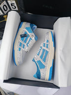 White and blue sneakers in an open box, lace-up style with blue accents