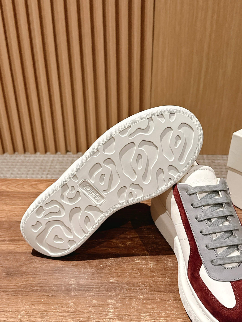 Alexander McQueen sneakers outsole view, white rubber tread with grey-and-burgundy upper