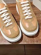 Two tan and beige low-top sneakers with white laces and white rubber sole