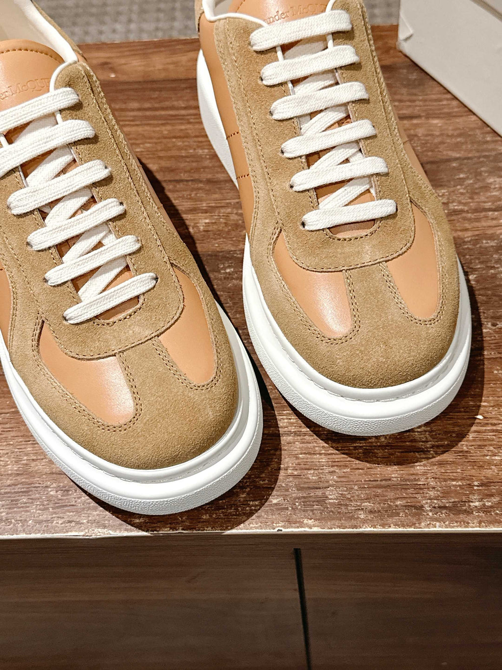 Two tan lace-up sneakers with white laces and suede quarter panels