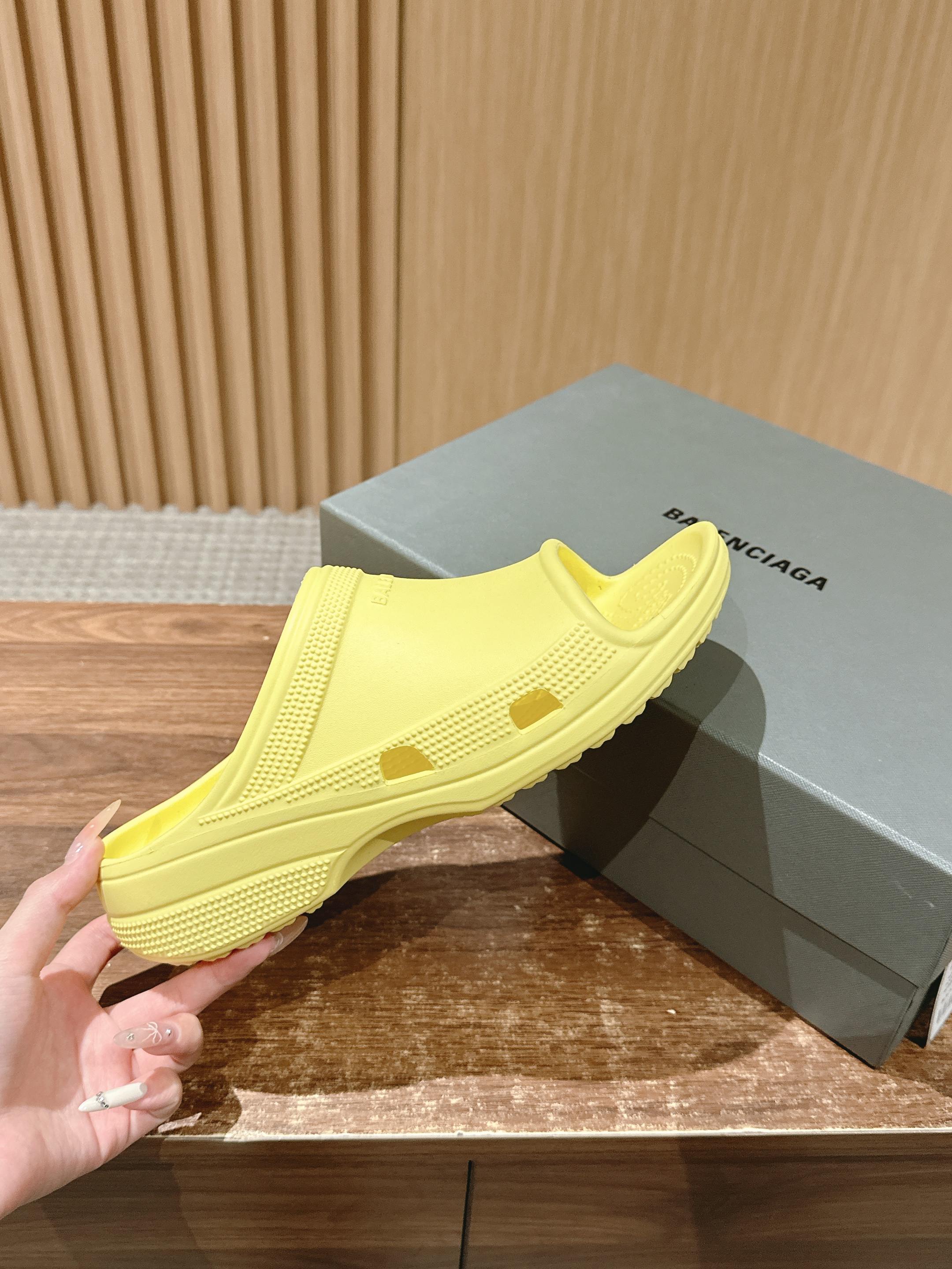 Balenciaga yellow slide sandal held near box, textured upper and footbed