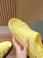 Balenciaga yellow slide sandals with textured sole, hand holding one pair
