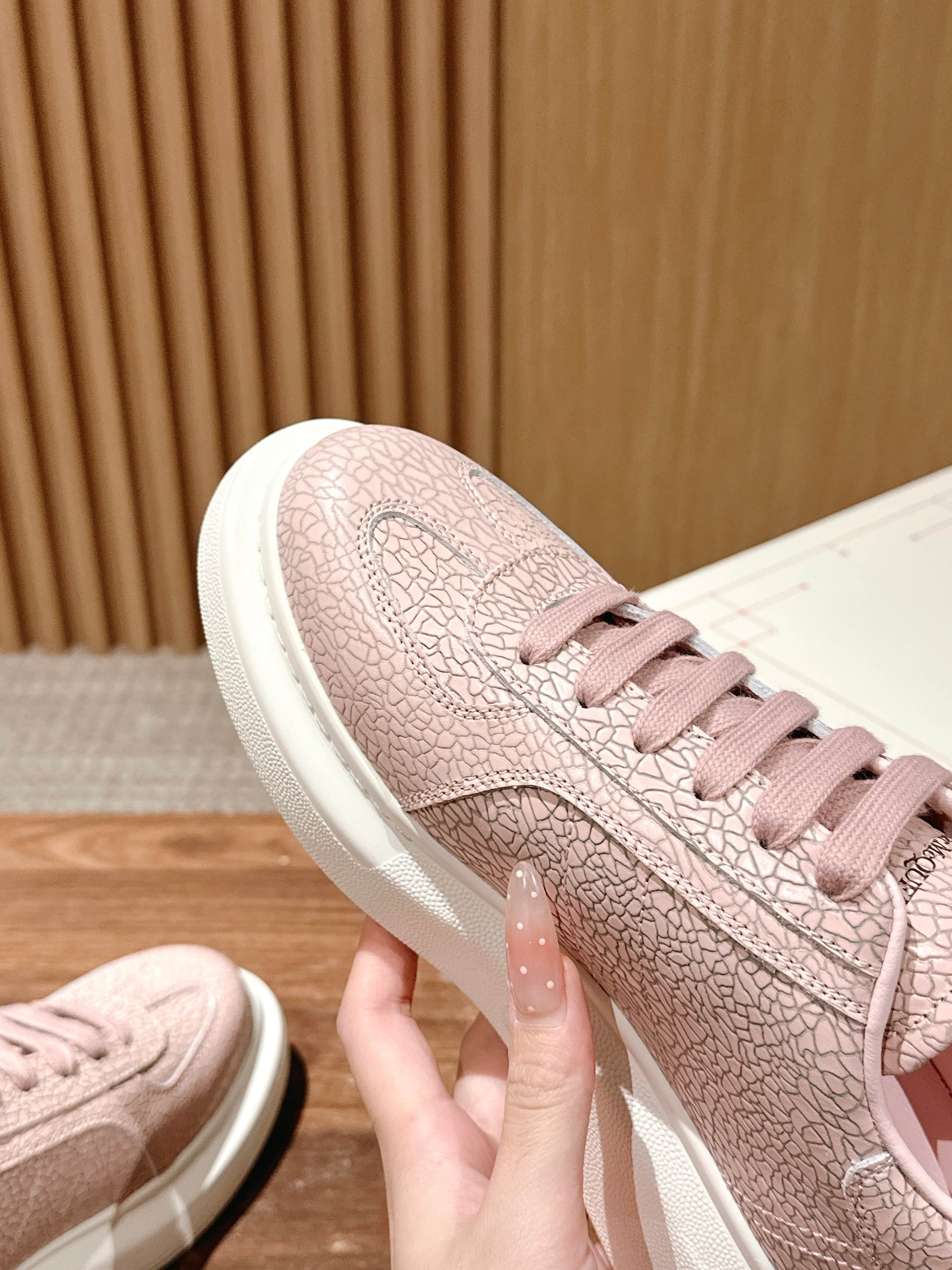 Pink Alexander McQueen lace-up sneaker side with textured pattern, white sole edge.