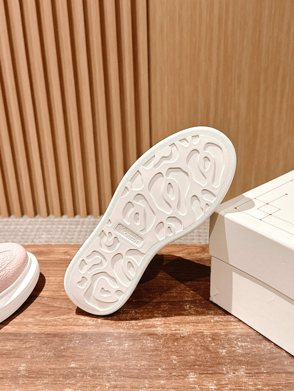 White outsole of Alexander McQueen pink sneaker, tread visible, heel side.