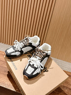 Two black and white unisex sneakers with lace-up tops on shoebox lids