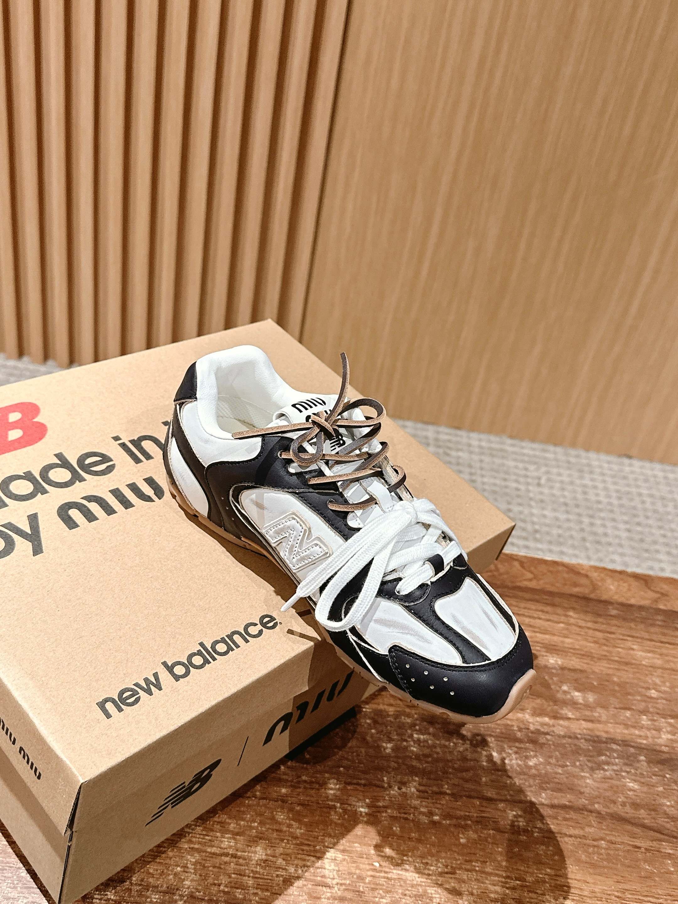 Black and white unisex lace-up sneakers resting on shoeboxes